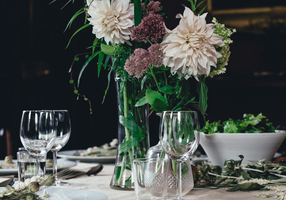 A dressed table with glassware, flowers and folded linen